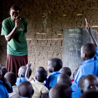 Lehrer erklärt der Klasse etwas, Junge zeigt auf in einem Caritas Projekt unterstützt von Schenken mit Sinn
